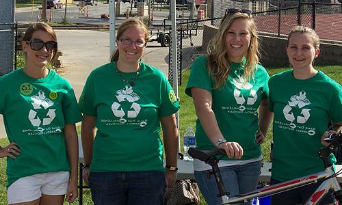 four women standing next to each other wearing recyling shirts.